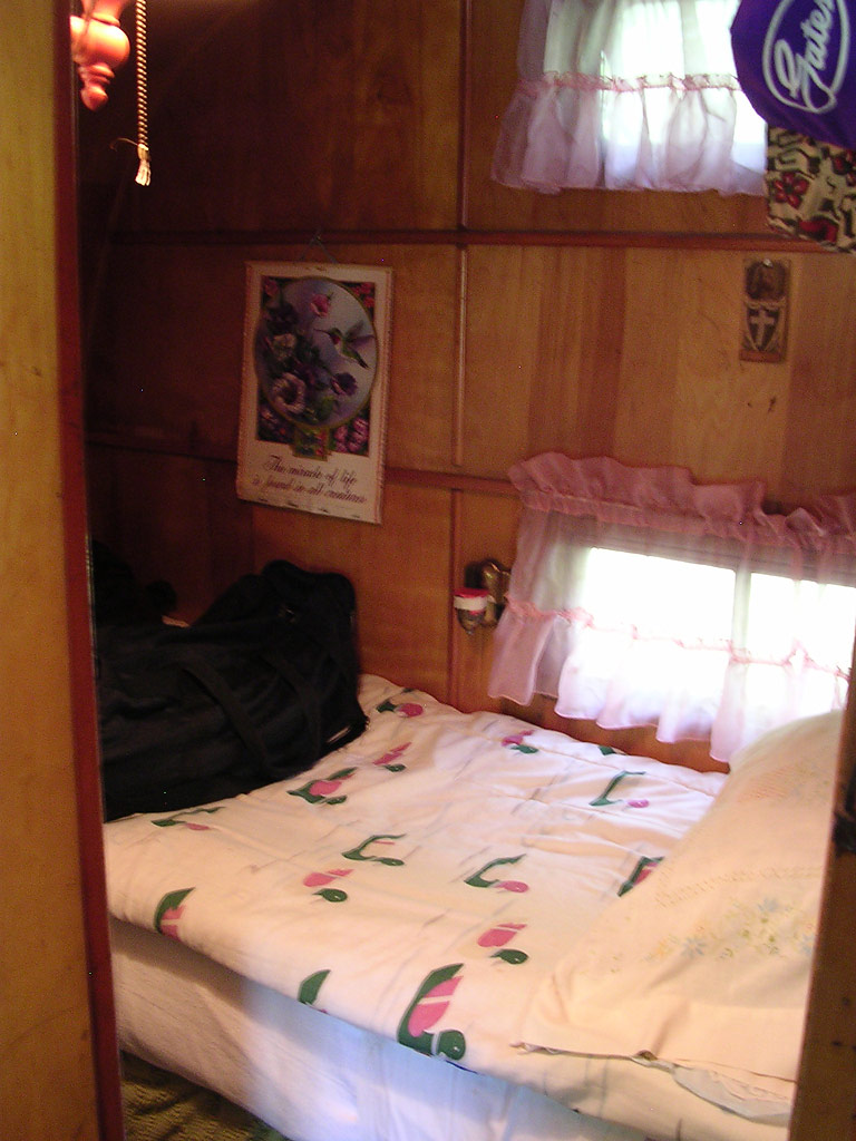 A small bed for one person in the back of the trailer.