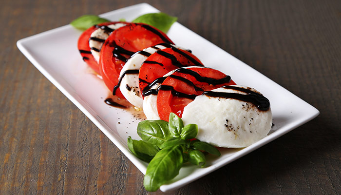 Caprese Salad Consisting Of Fresh Tomatoes, Basil, Mozzarella Cheese, Olive Oil, And Balsamic Vinegar