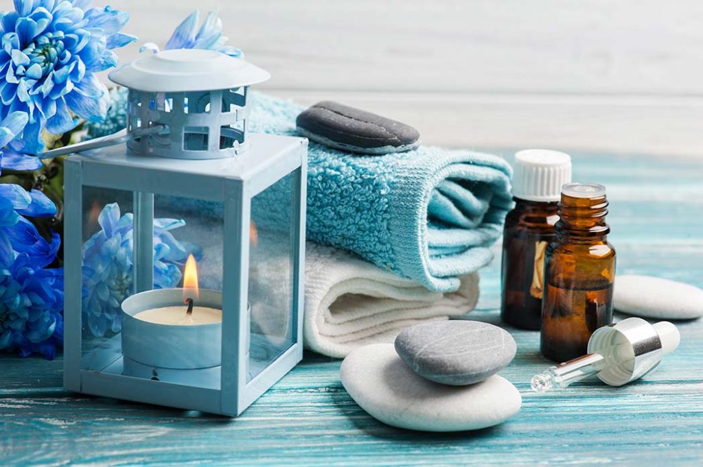 Aqua and blue theme with tea lite lantern, essential oils, massage stones, oil dropper, and towel