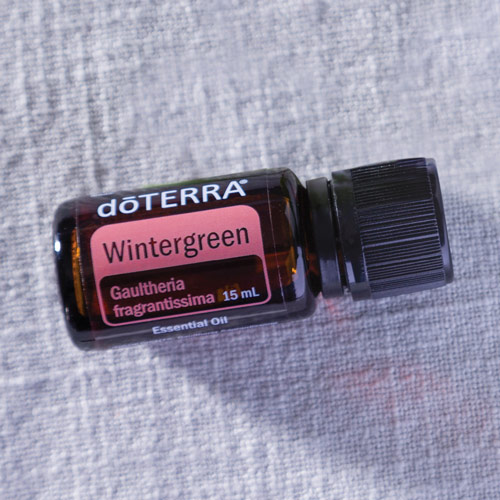 Wintergreen oil bottle laying over white linen
