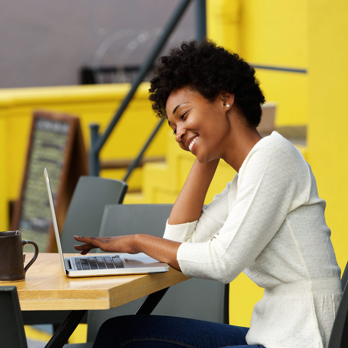 Photo of Woman sitting outside a cafe with a laptop