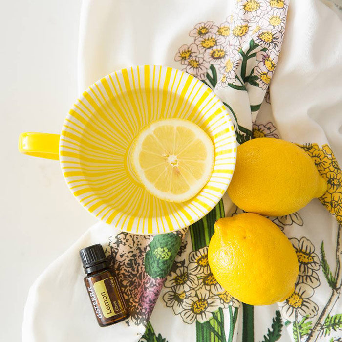 Photo of doTERRA lemon essential oil with lemons and tea cup